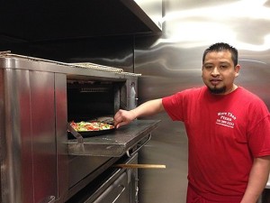 Antonio Moran puts a tomato, broccoli and red pepper pizza in the oven. More Than Pizza new haven