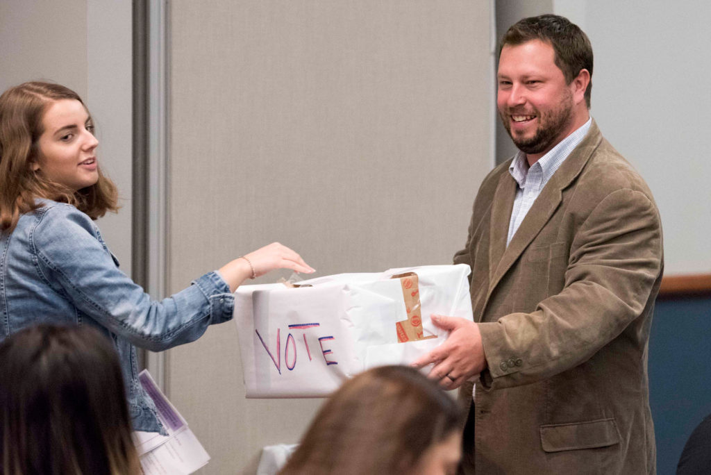 A high school student submits her ballot during High School Journalism Day, while speaker Paul Singley looks on. | Vern Williams photo.
