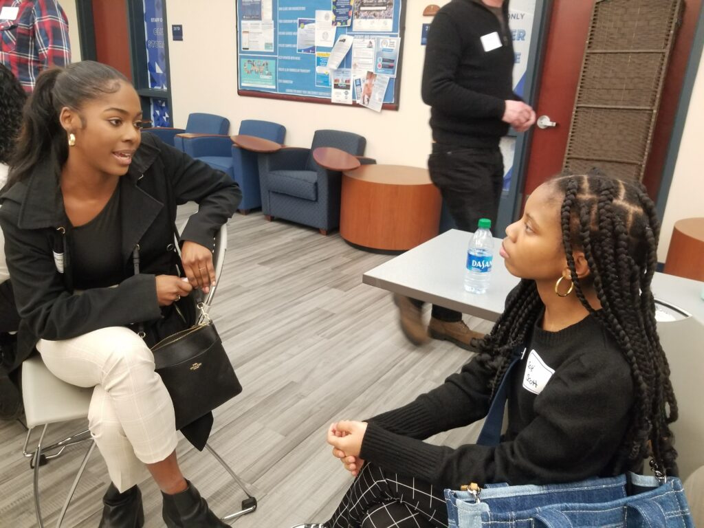 Two woman talk in a conference room during a networking event.